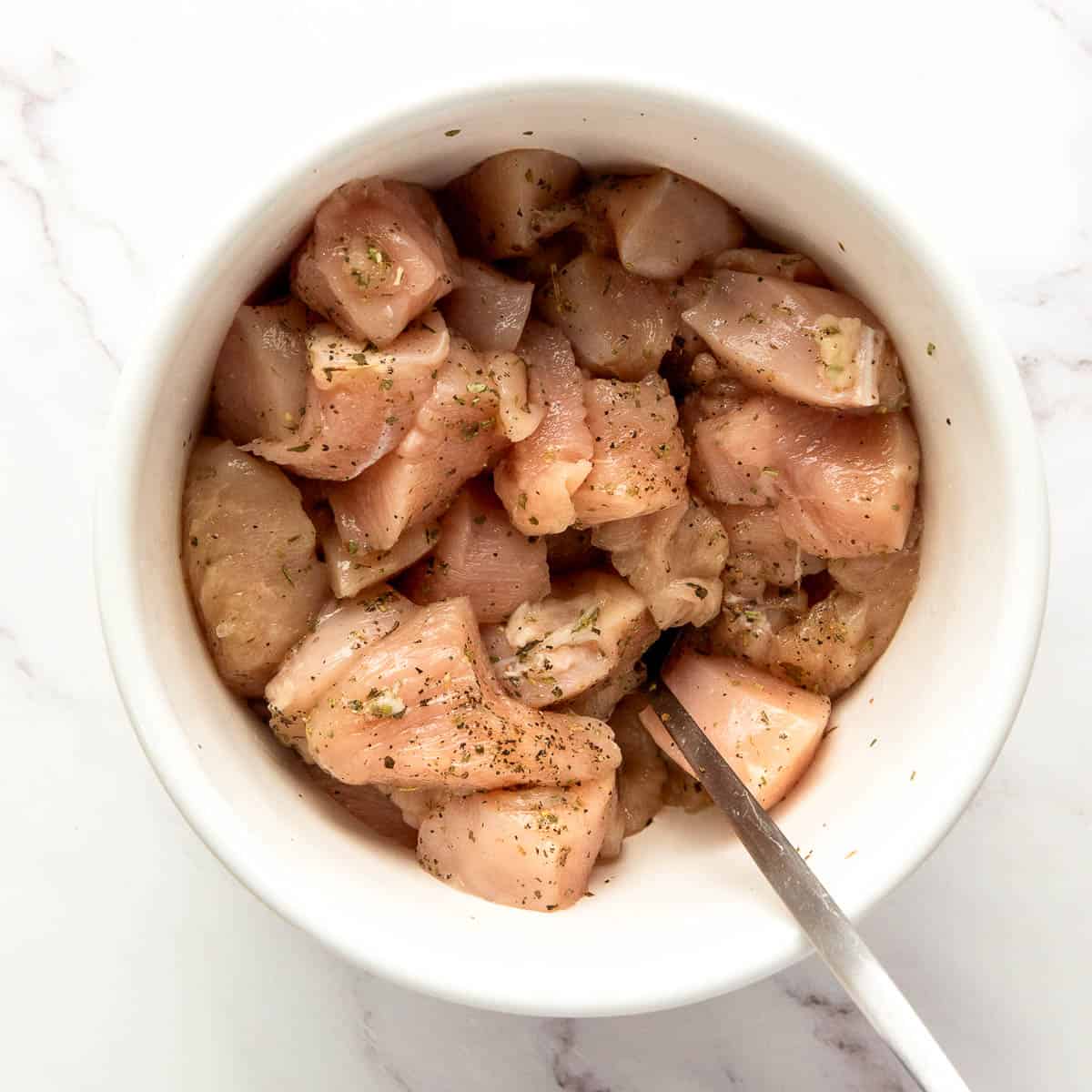 Seasoned chicken in a mixing bowl.