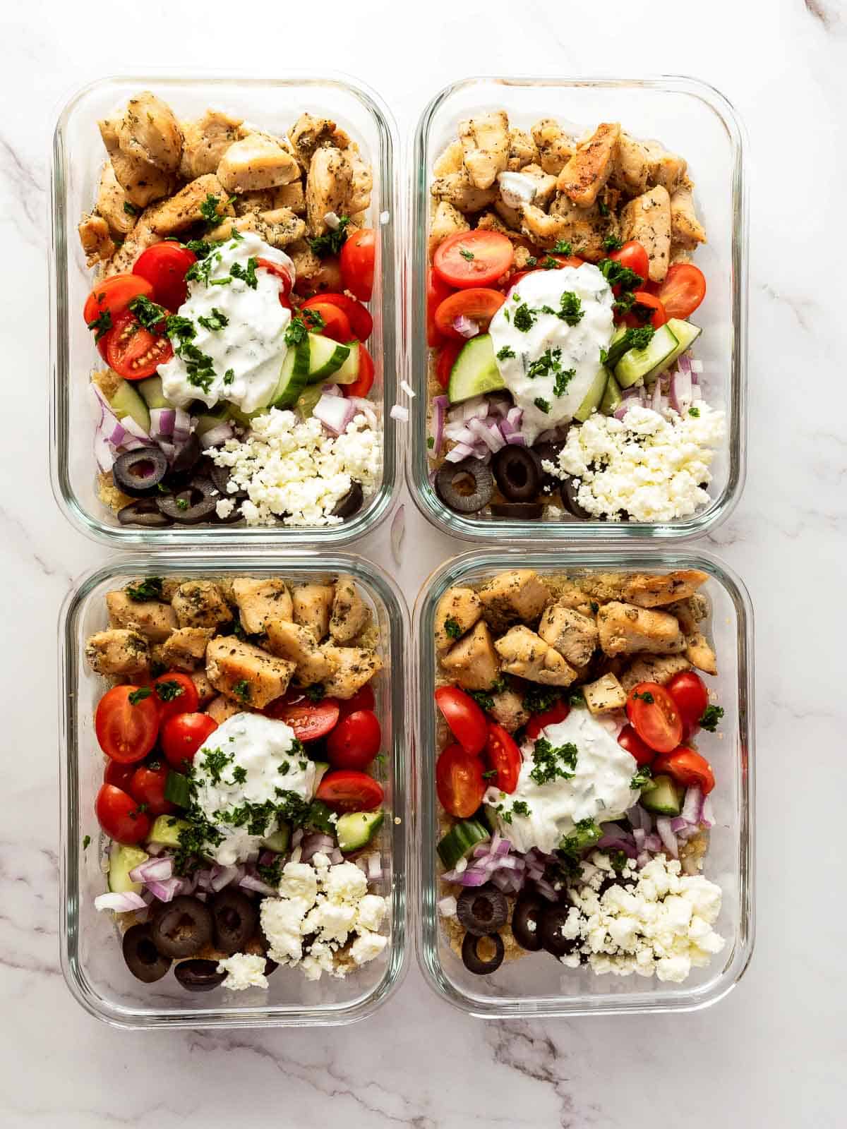 Fully assembled Mediterranean chicken bowls on a white surface.