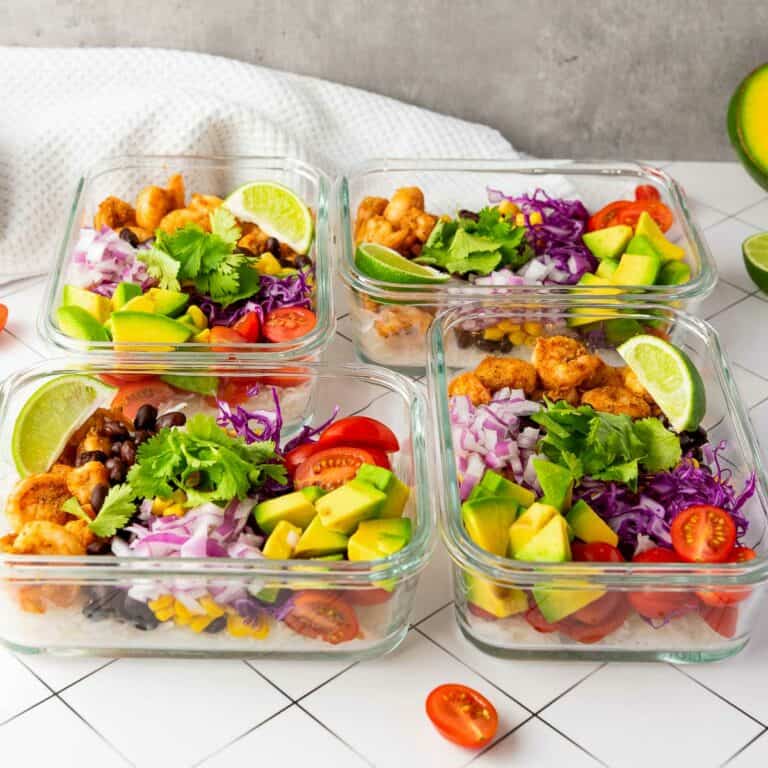 Four containers of shrimp taco rice bowls placed on a white surface.