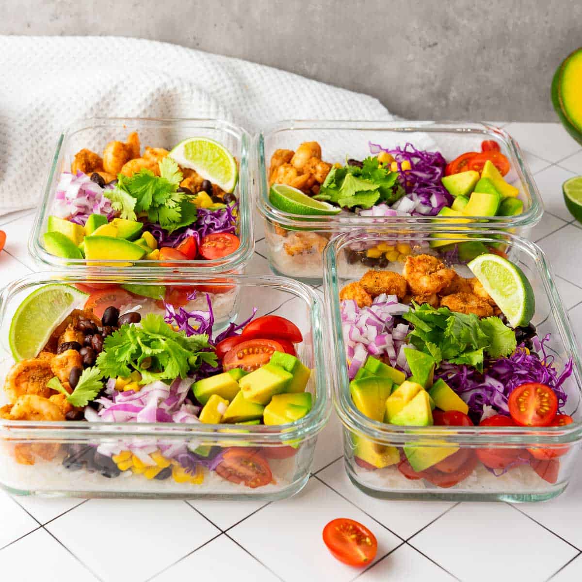 Four containers of shrimp taco rice bowls placed on a white surface.