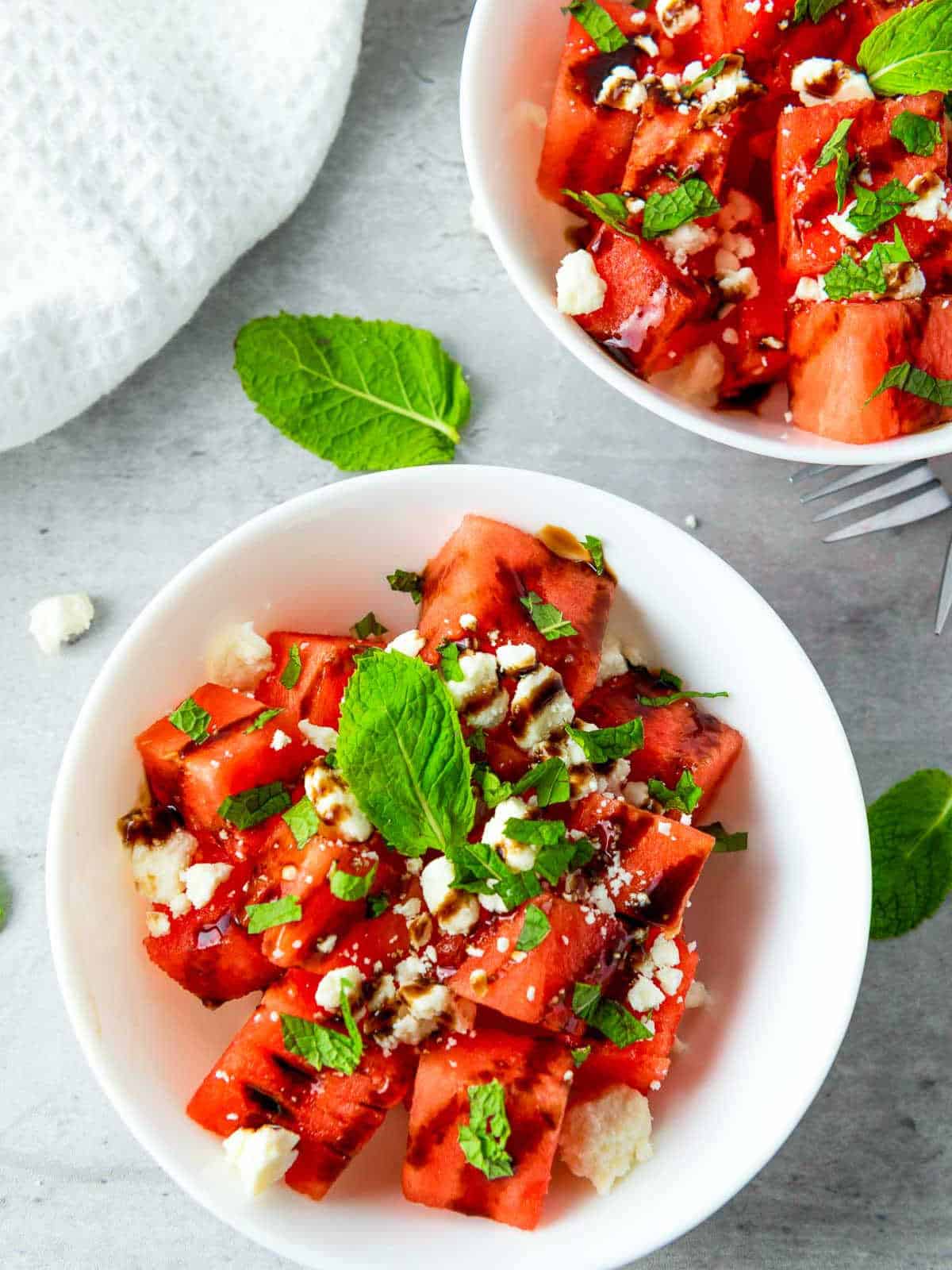 Close up of salad bowl with fork and another white bowl in the background.