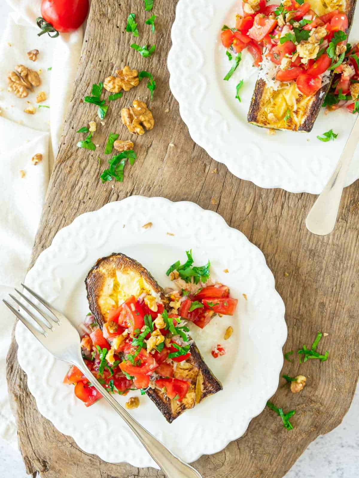 Two plates of zucchini tomato salad on white serving plates.