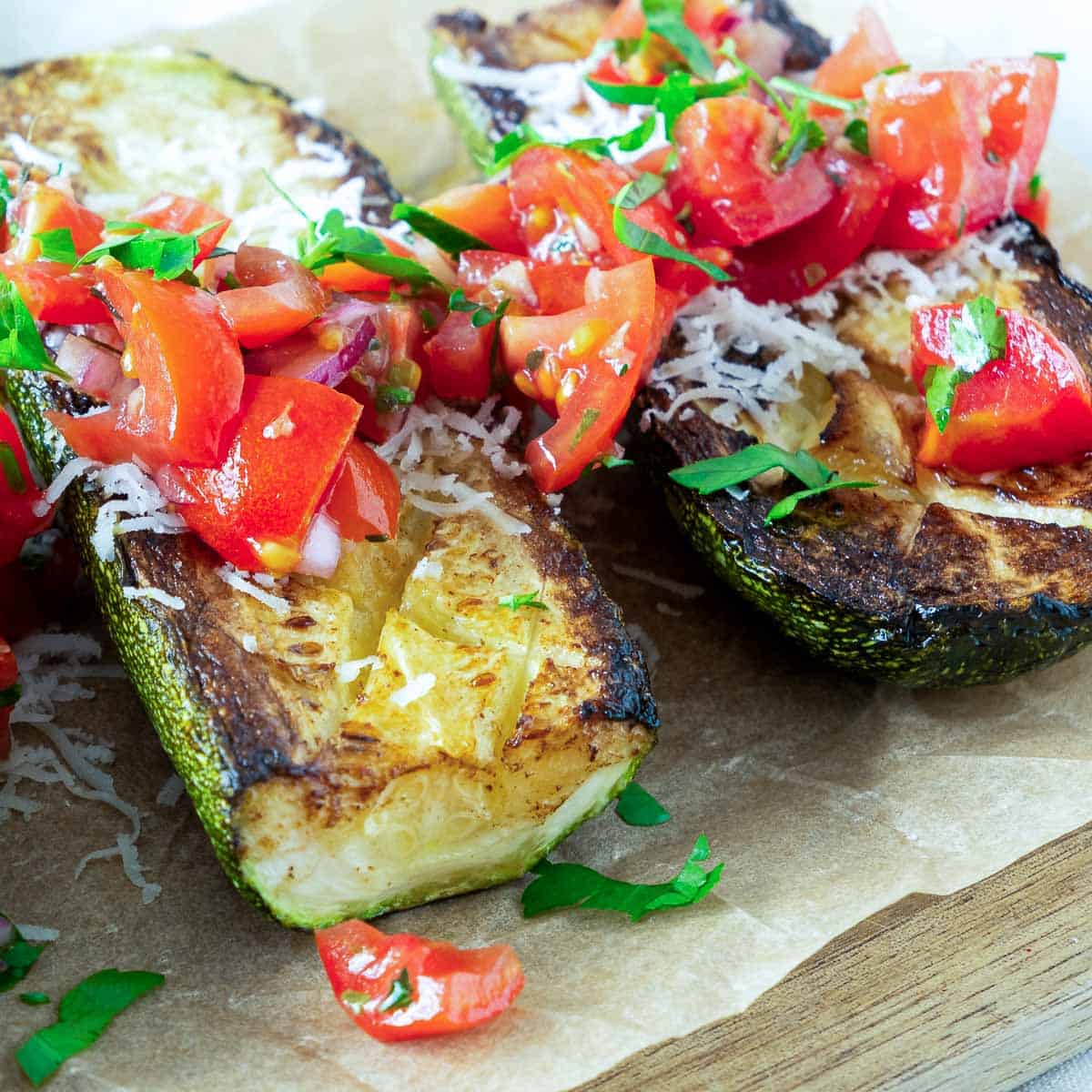 Close up of zucchini tomato salad placed on a wooden board lined with parchment paper.