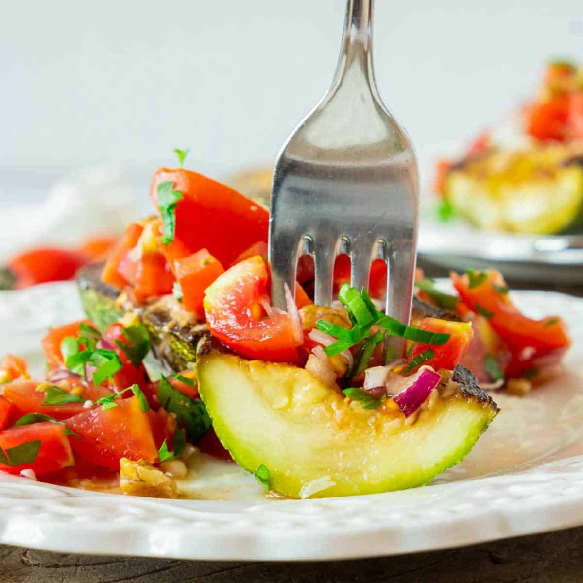 Fork inserted into zucchini on white plate.