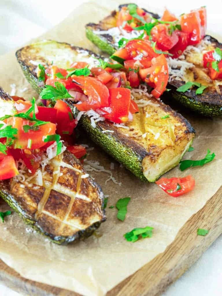 Assembled zucchini tomato salad placed on wooden board.