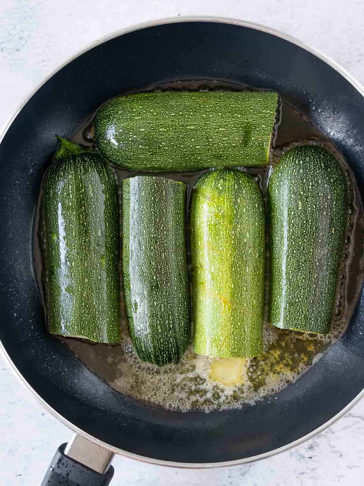 Zucchini in frying pan with oil and butter.