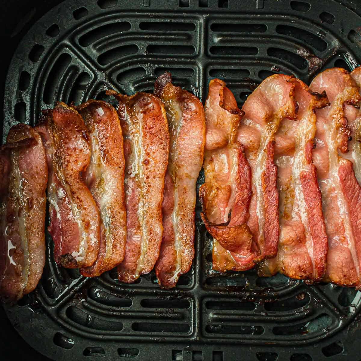 Cooked bacon in air fryer basket.