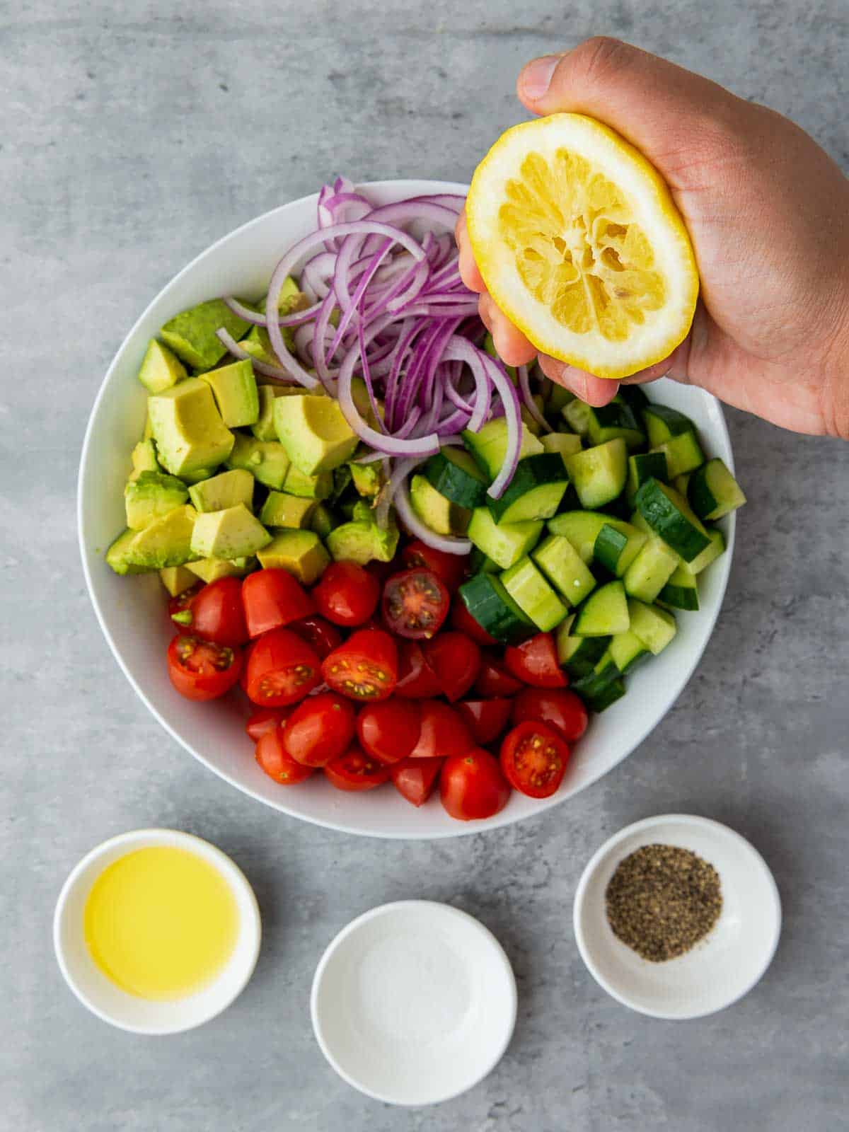 Lemon squeezed on the salad vegetables placed in a mixing bowl.