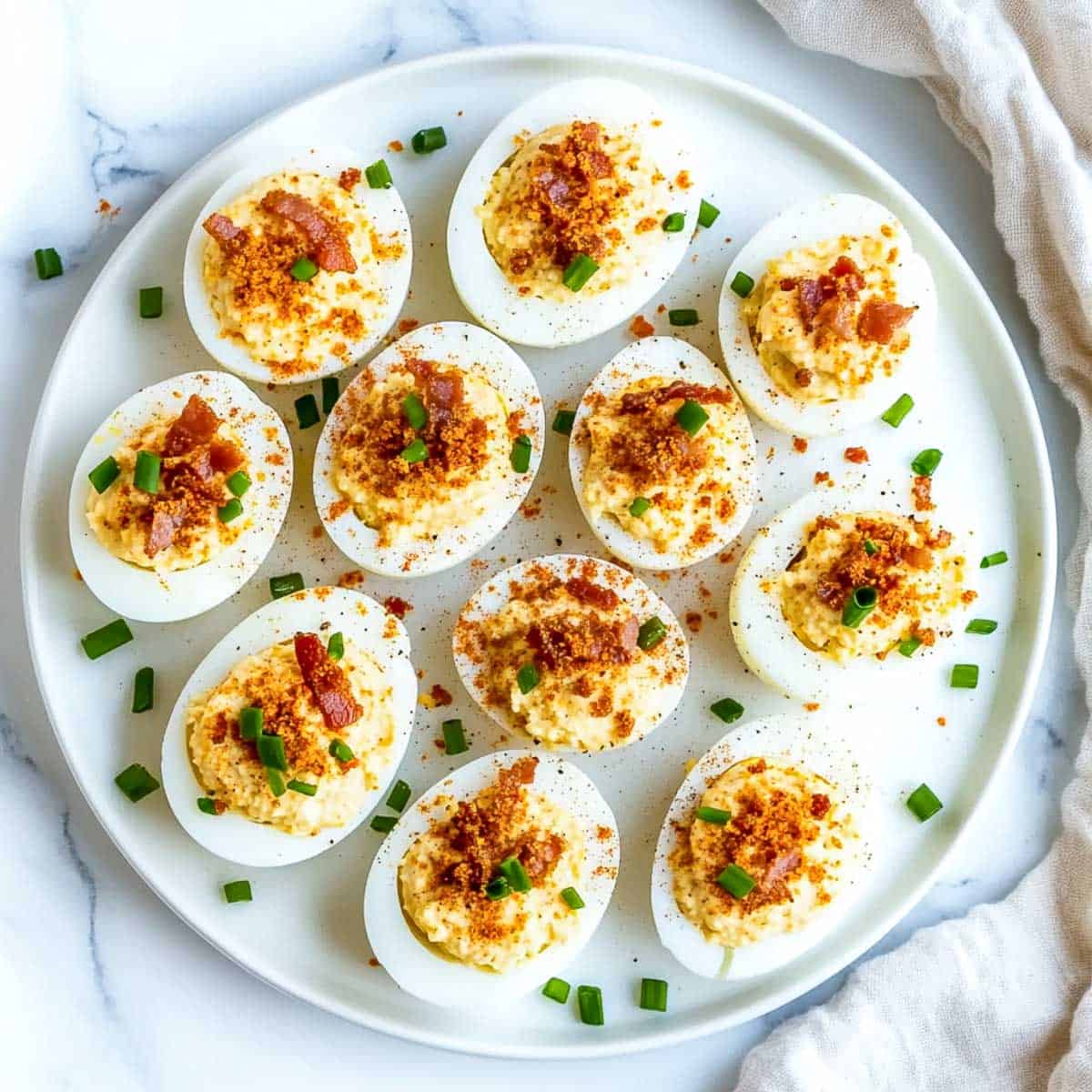 Close up view of bacon and cheddar deviled eggs on a serving plate.