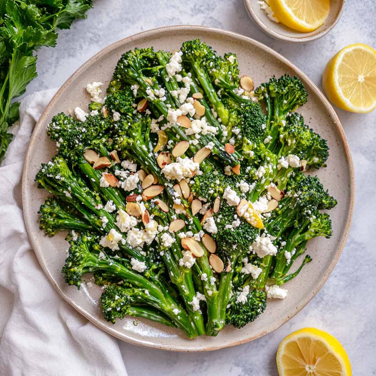 Broccolini salad topped with almonds with lemon slices in the background.