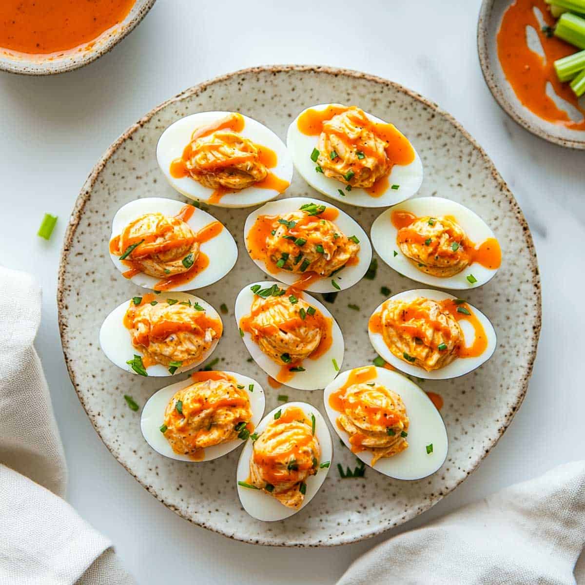 Buffalo deviled eggs drizzled with buffalo sauce on a serving plate.