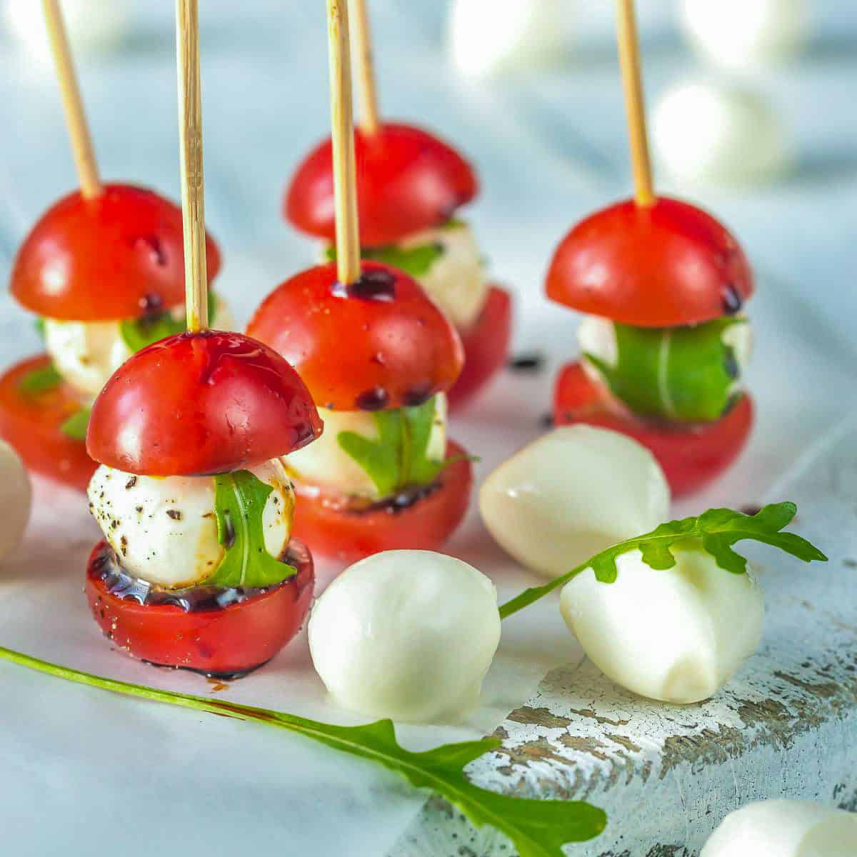 Caprese salad skewers on a white plate.