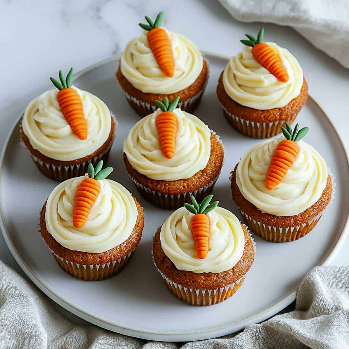 Carrot cake cupcakes topped with carrot cake toppers.