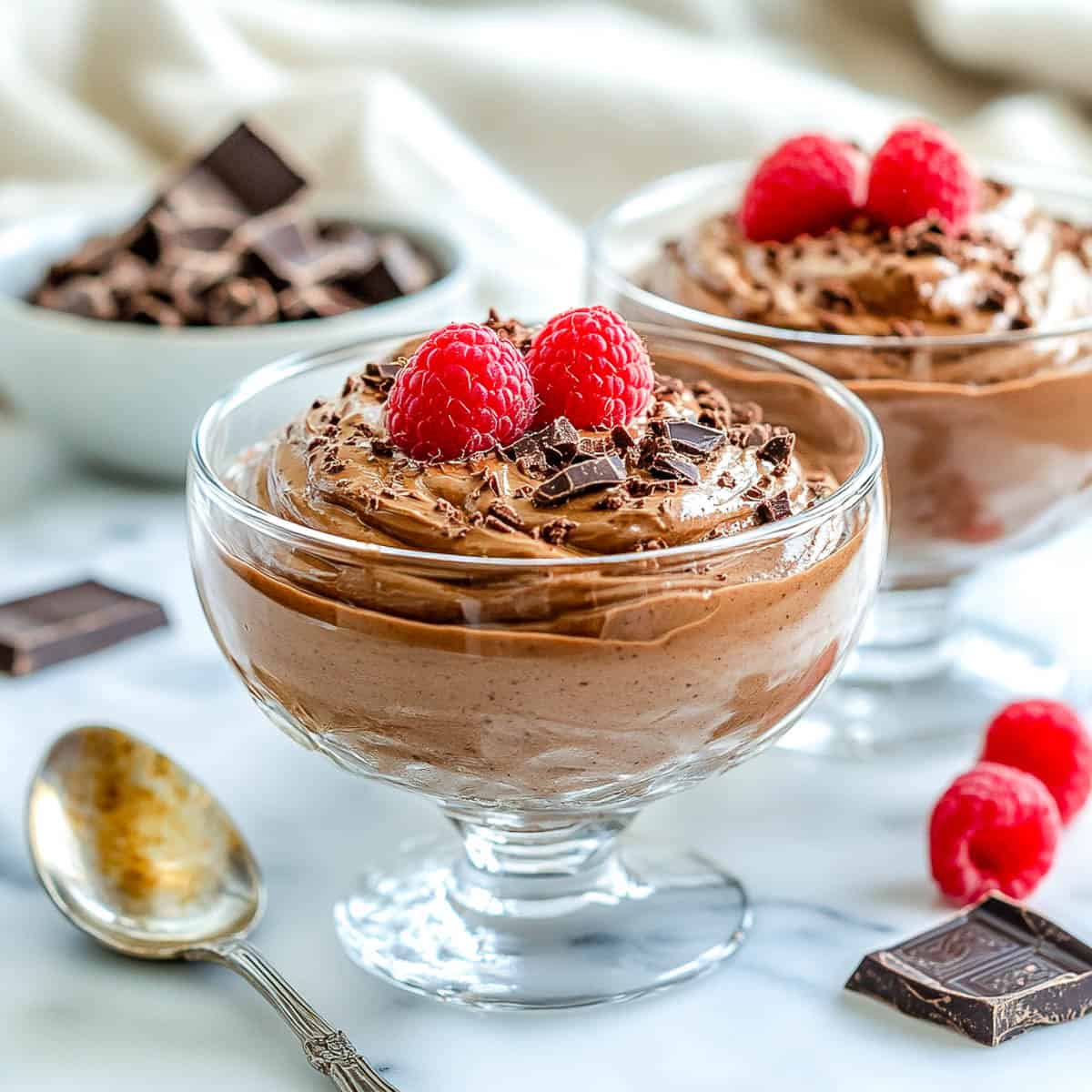 Side view of two bowls of cottage cheese mousse topped with raspberries.