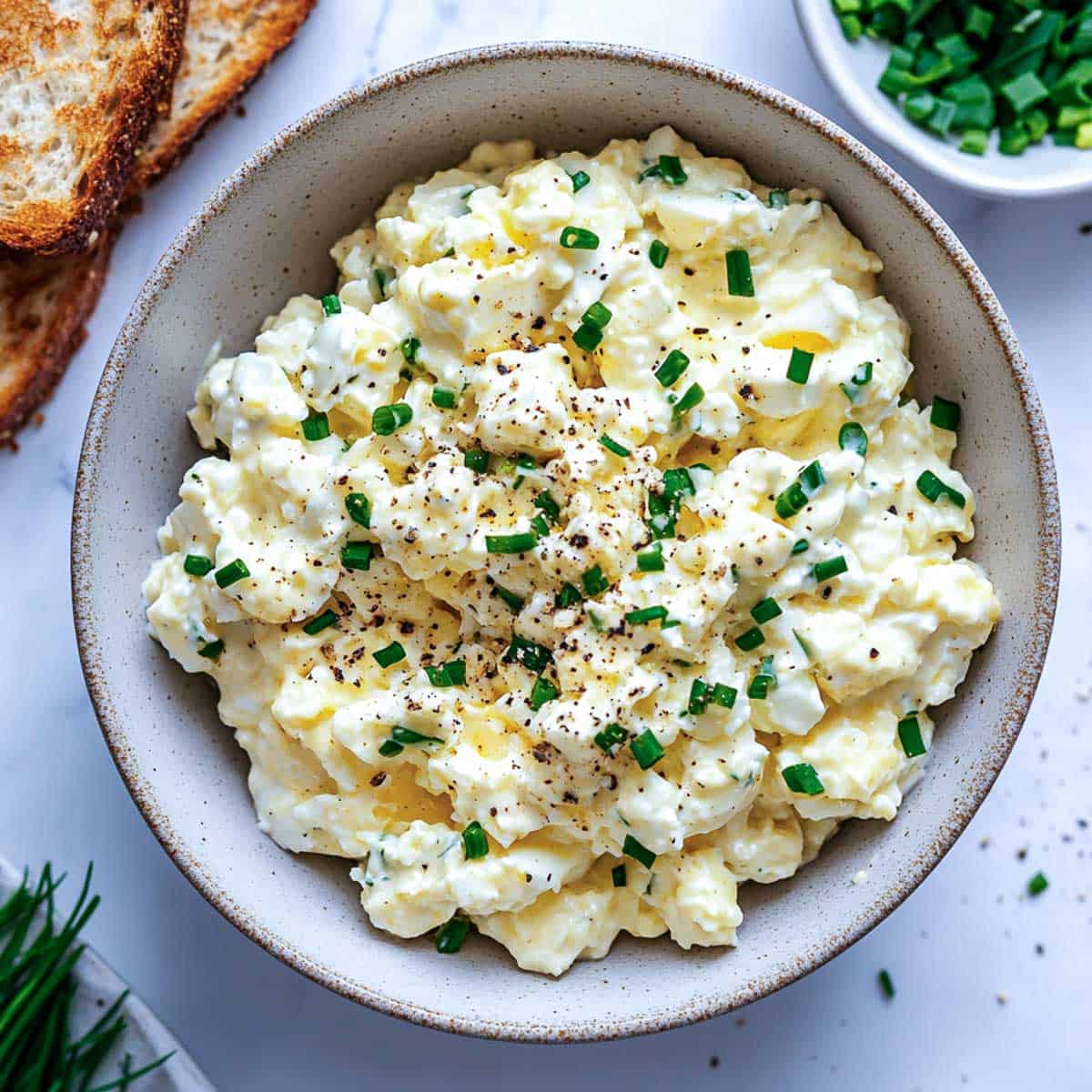 A bowl of cottage cheese egg salad with toasted bread in the background.