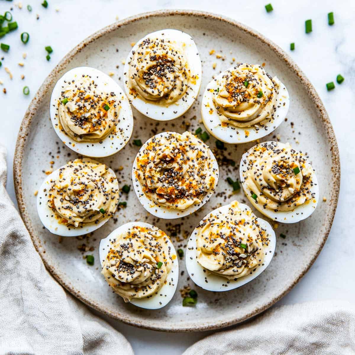 A plate of deviled eggs seasoned with everything bagels seasoning.