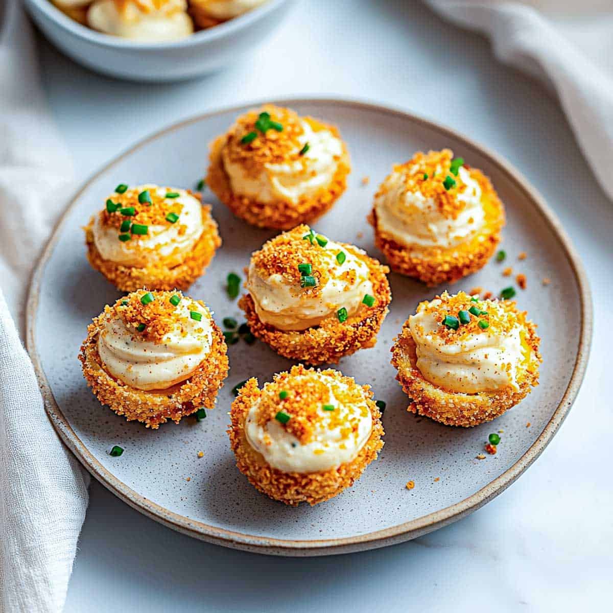 Side view of fried deviled eggs on a grey plate.