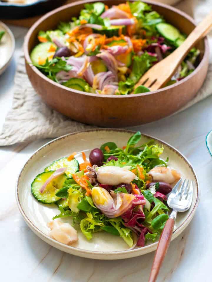 Side view of calamari garden salad on a white serving plate.