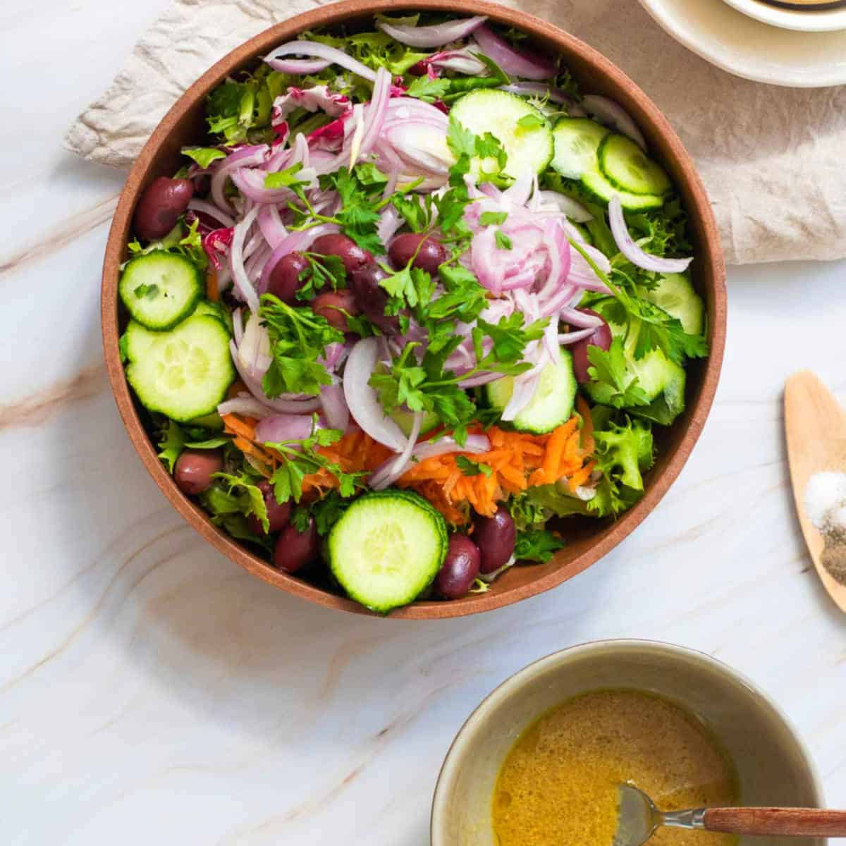 Salad ingredients in a wide bowl along with dressing in a small bowl.