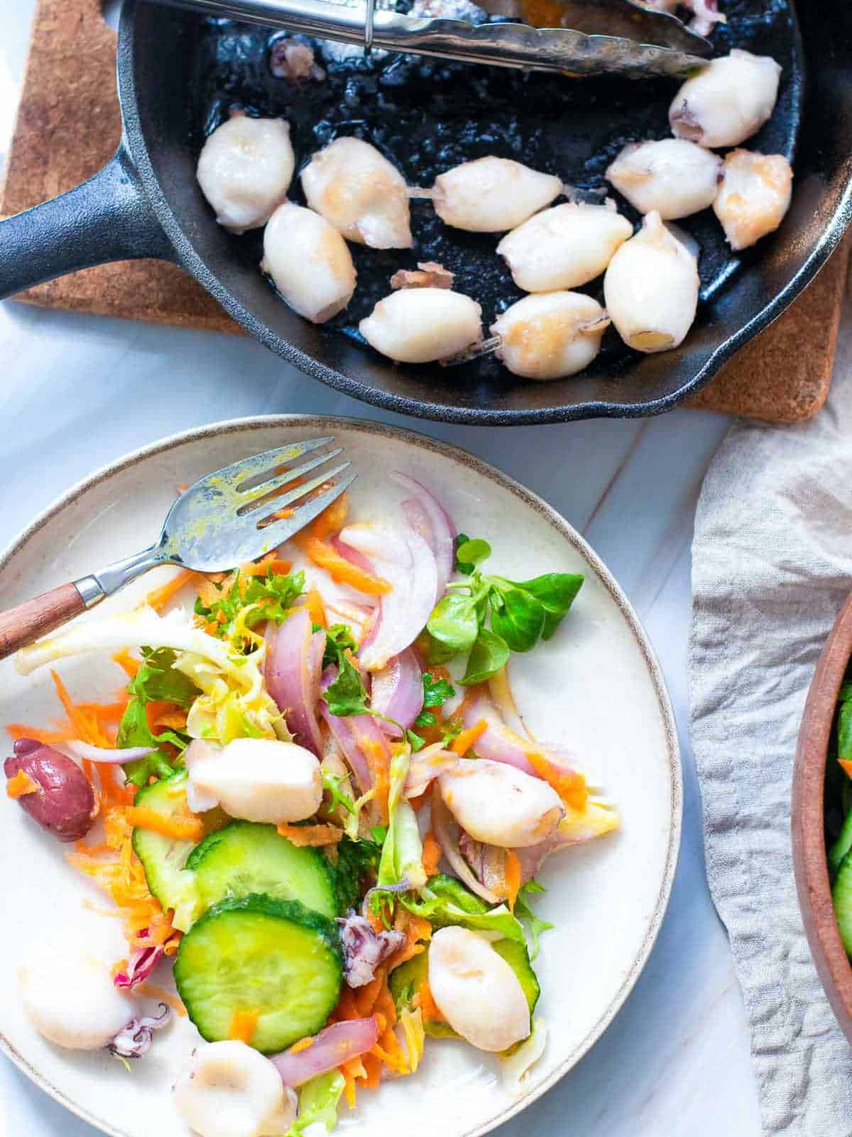 Garden salad topped with calamari on a serving plate.