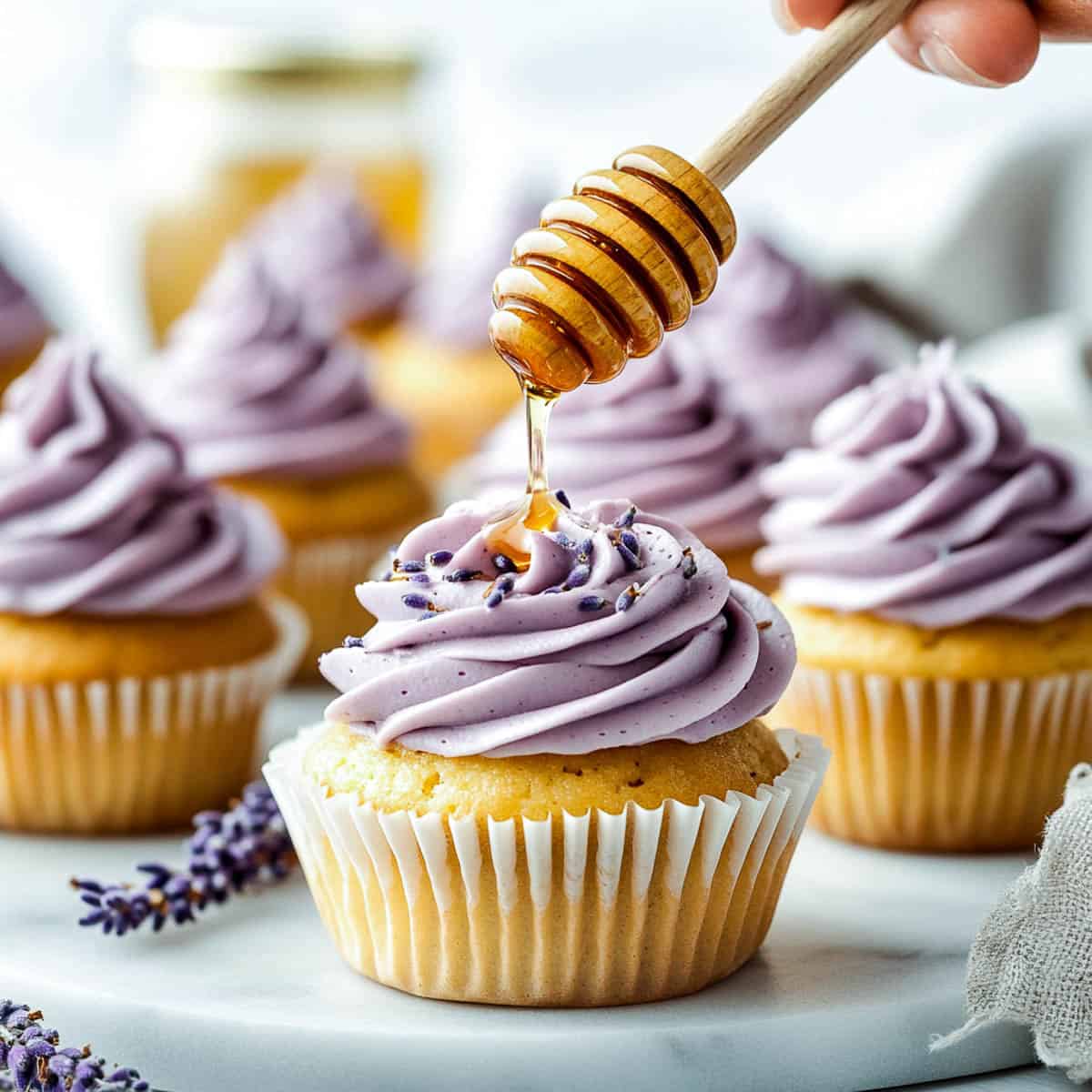 Lavender honey cupcakes on a plate with honey drizzle.