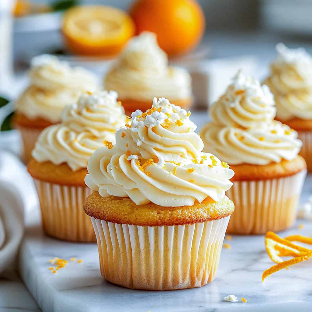 Orange blossom cupcakes side view with oranges in the background.