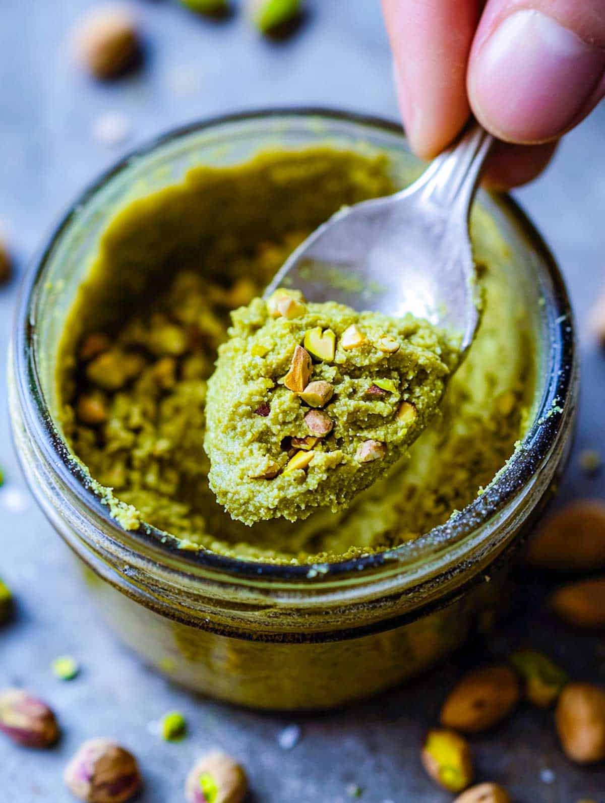 A spoonful of pistachio paste over the jar.