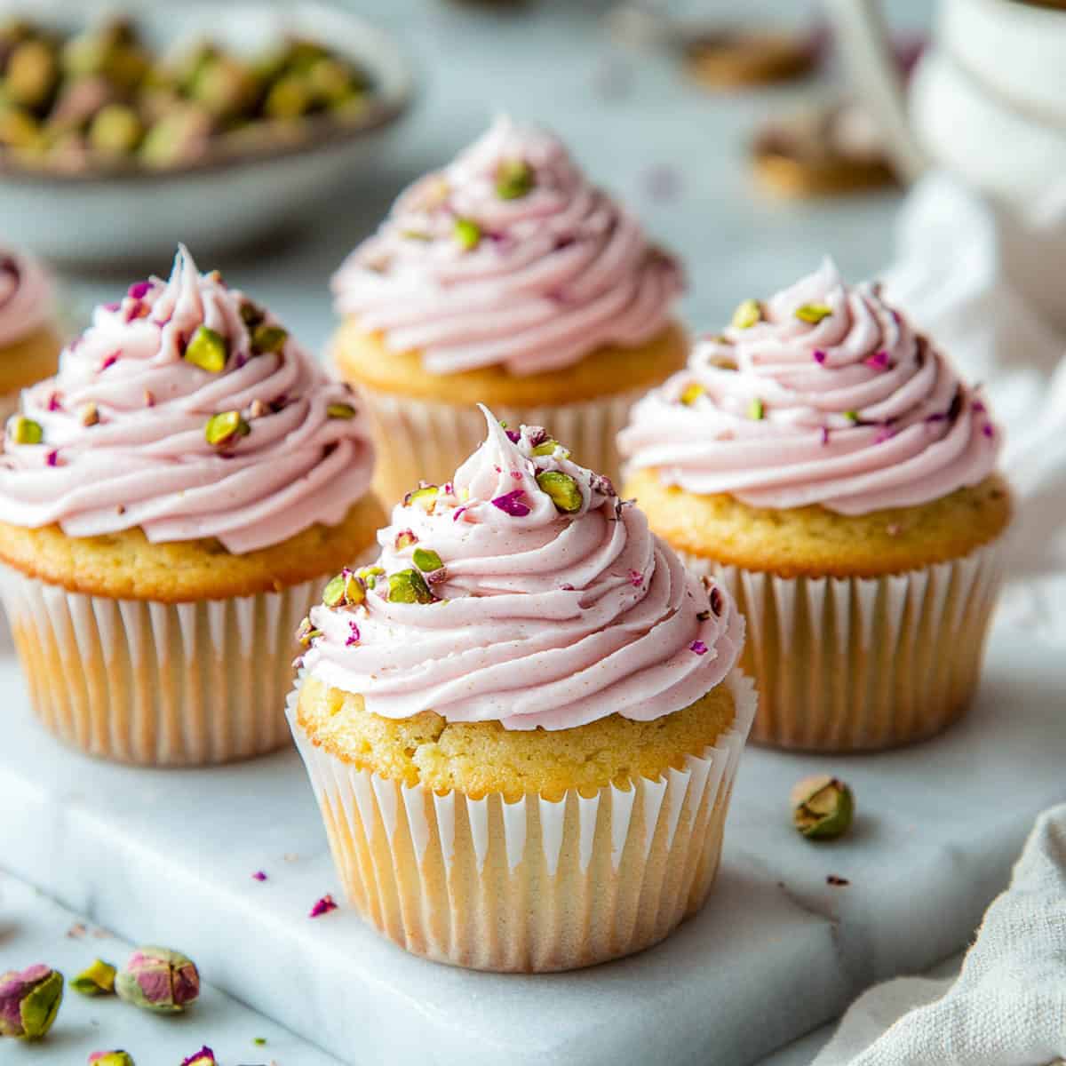 Pistachio rose cupcakes topped with chopped pistachios.