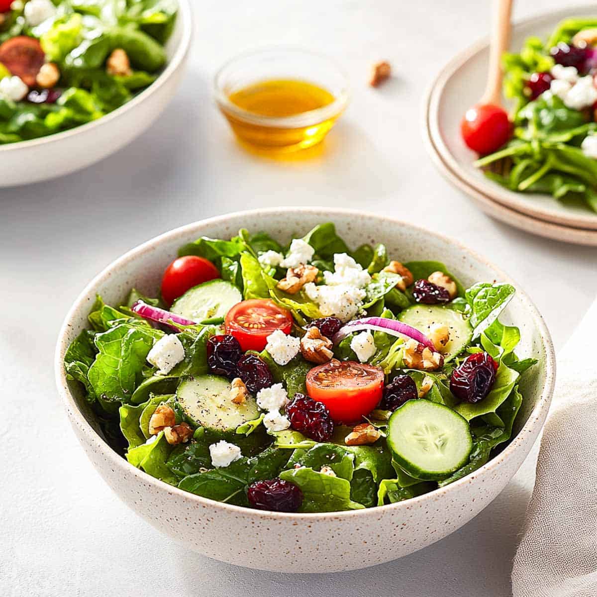 Spring mix salad served on to plates along with the salad bowl.