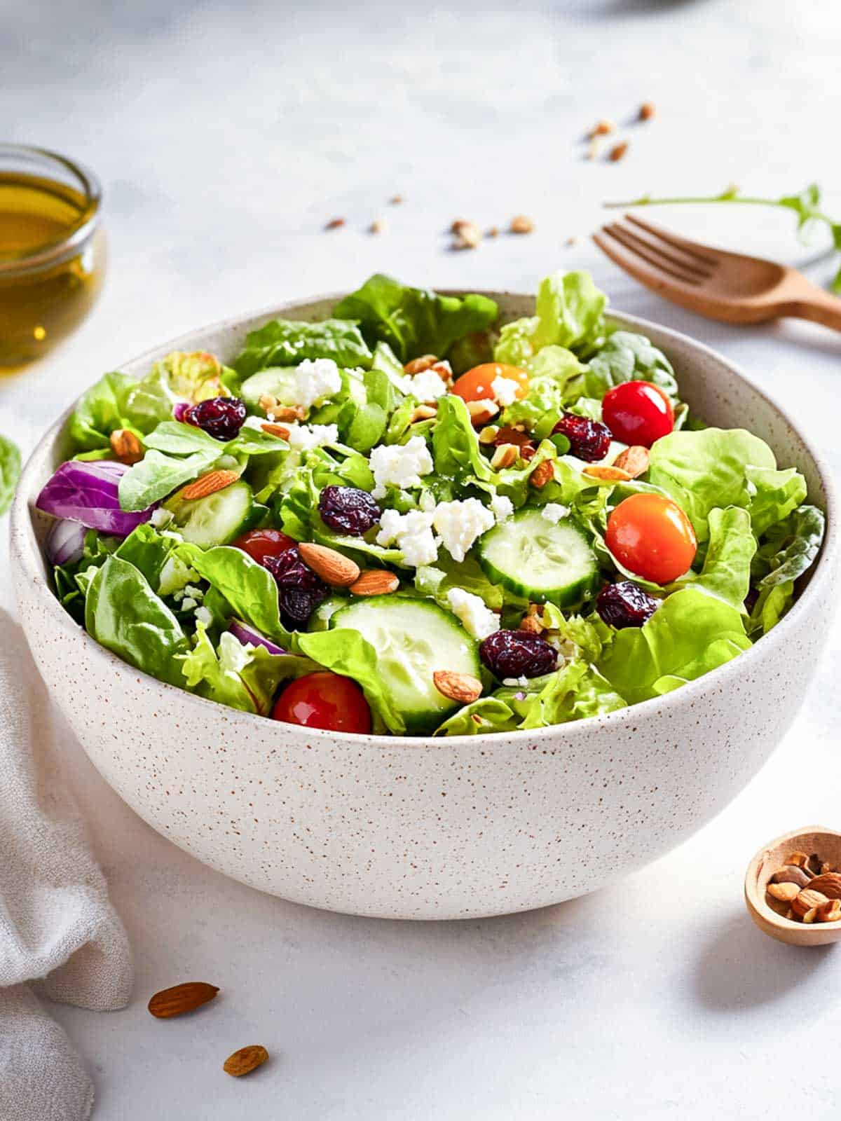 Spring mix salad in a white bowl placed on a white surface.