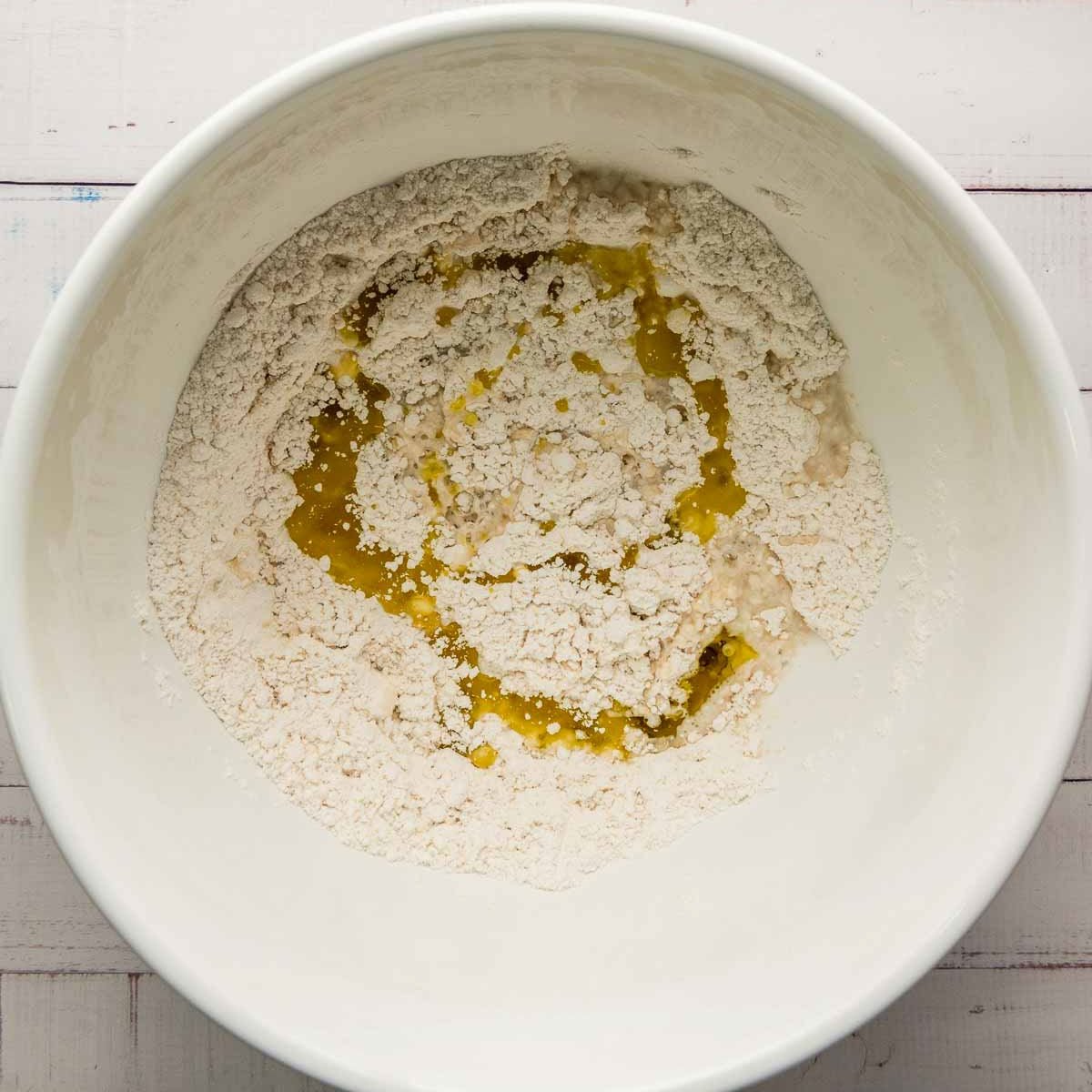 Dry ingredients with olive oil and warm water added in the center, ready to mix.