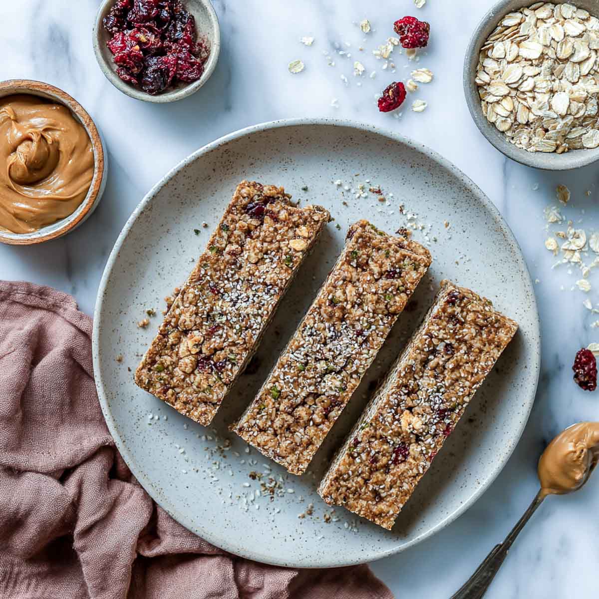 Three vegan protein bars with oats, nut butter, and seeds on a ceramic plate for low calorie high protein breakfast.