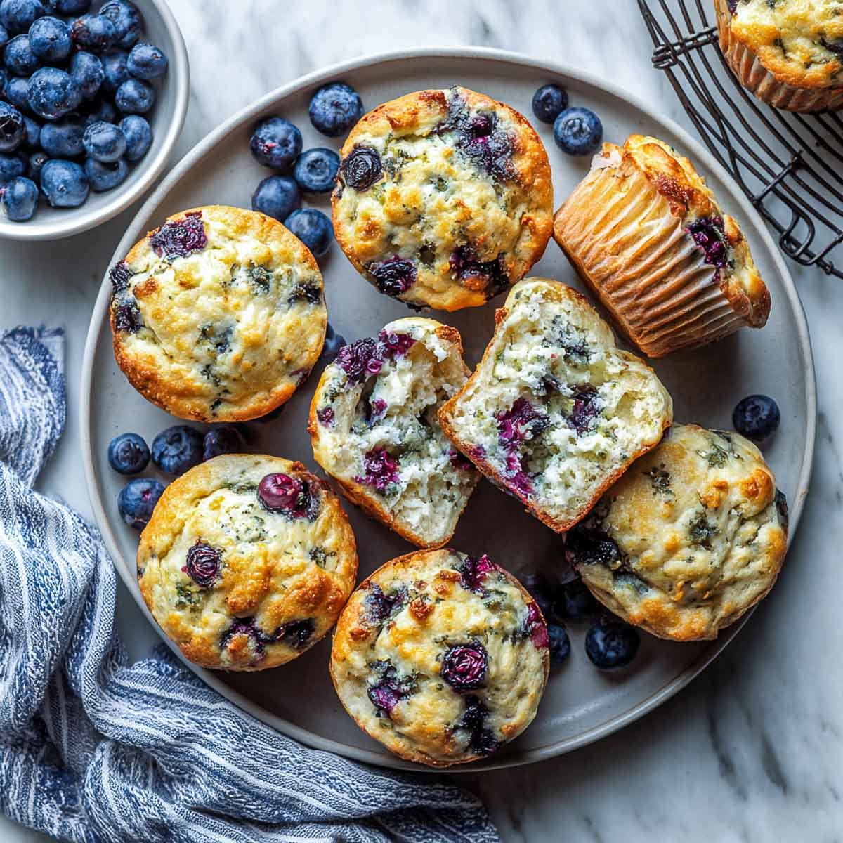 Top-down view of blueberry muffins with cottage cheese on grey plate and striped napkin.