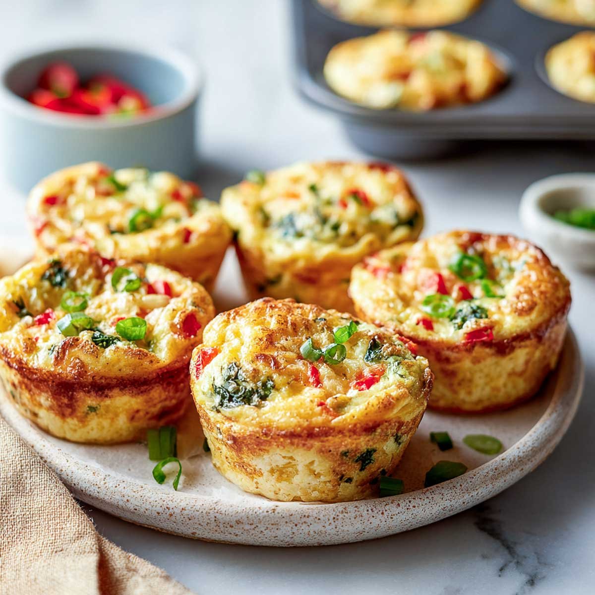 Angled view of colorful egg muffins with cottage cheese, red peppers, spinach, and scallions.
