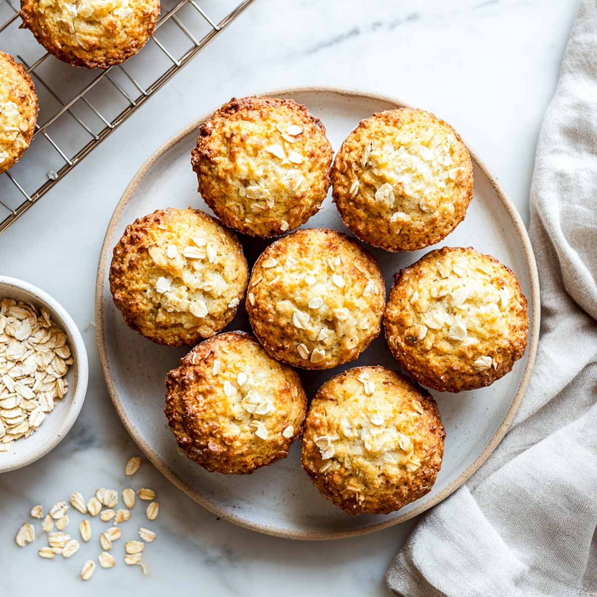 Top-down view of oatmeal muffins with cottage cheese on a ceramic plate and scattered oats.