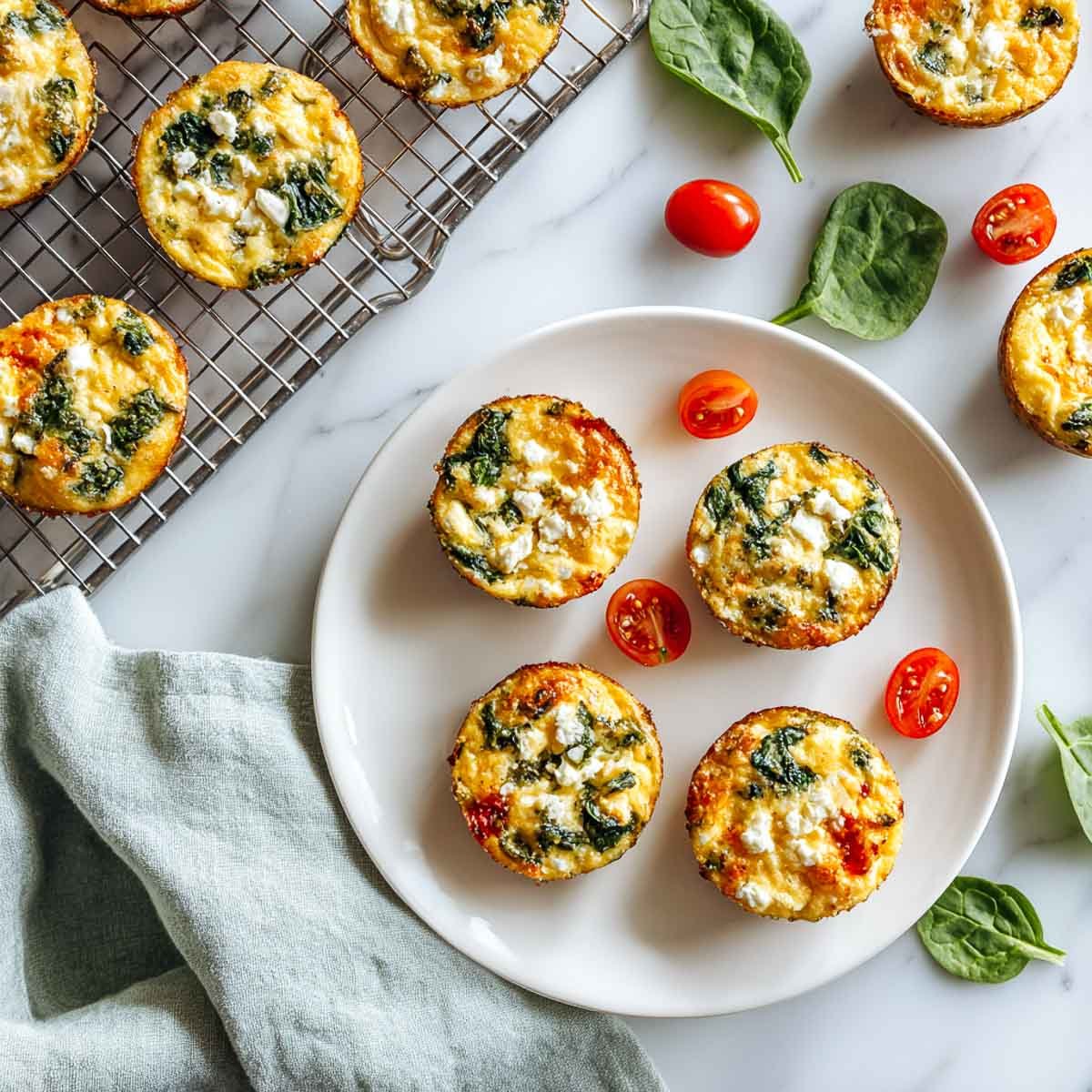 Top-down view of spinach and feta egg muffins with cherry tomatoes and spinach.