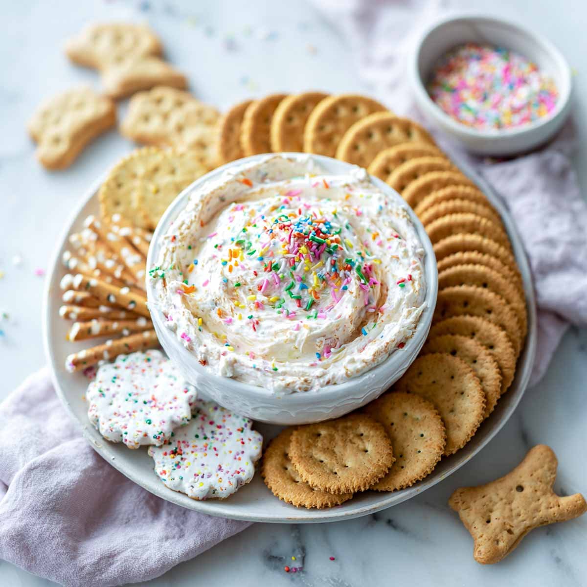 Funfetti dip with sprinkles in a bowl, served with crackers and animal cookies.