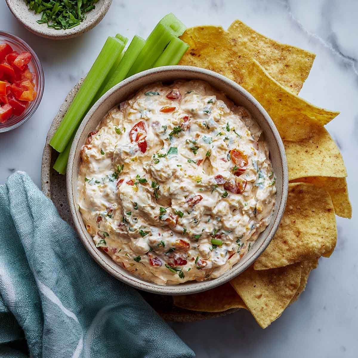 Creamy ranch Rotel dip in bowl with chips and celery sticks.