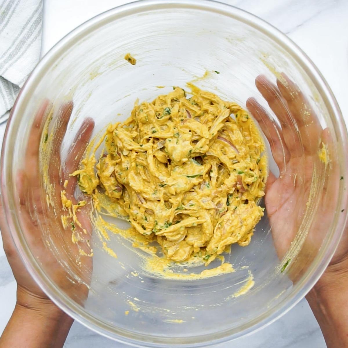 Thick onion pakora batter mixed and ready in a glass bowl.