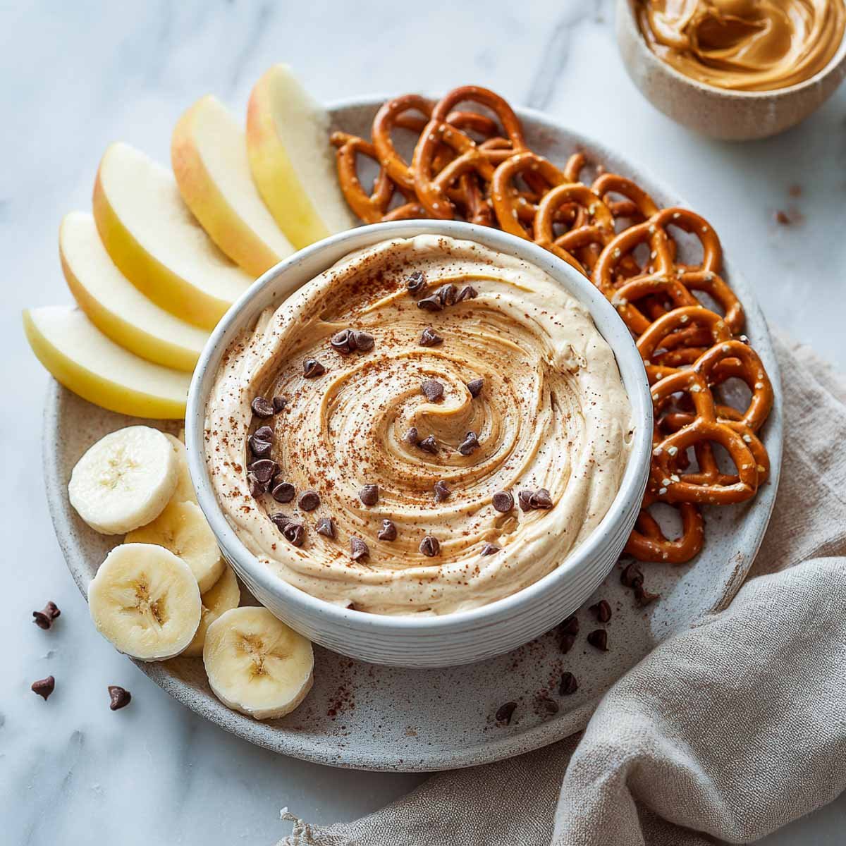 Peanut butter yogurt dip with chocolate chips, served with banana, apple, and pretzels.
