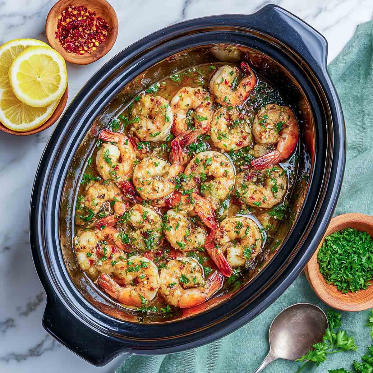 Juicy garlic butter shrimp with tail-on in crockpot.
