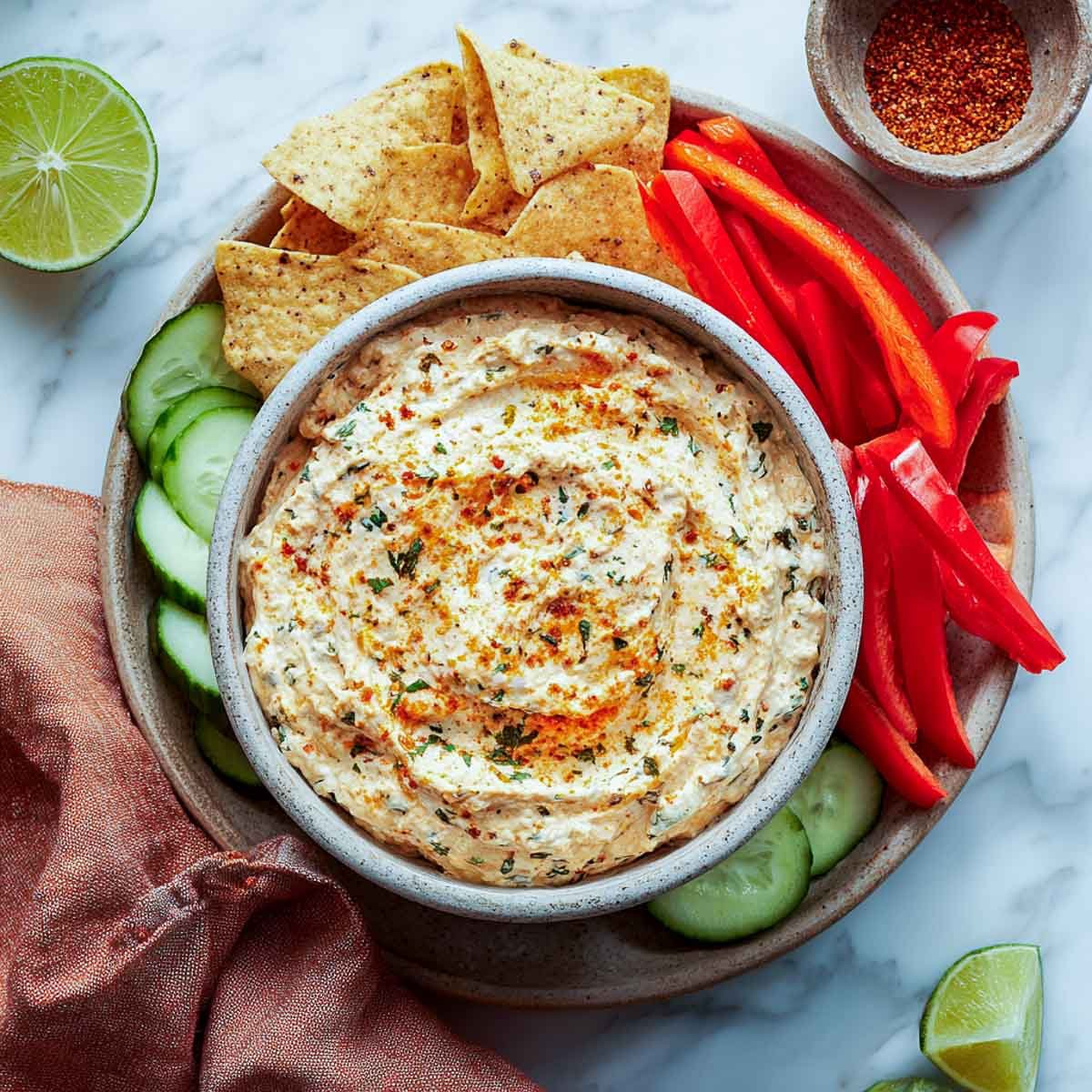 Creamy ranch dip with herbs and spices served with peppers, chips, and cucumbers.