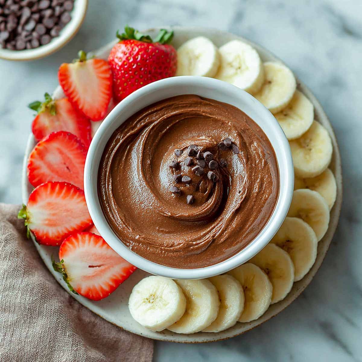 Chocolate dip with mini chips served with bananas and strawberries on the side.