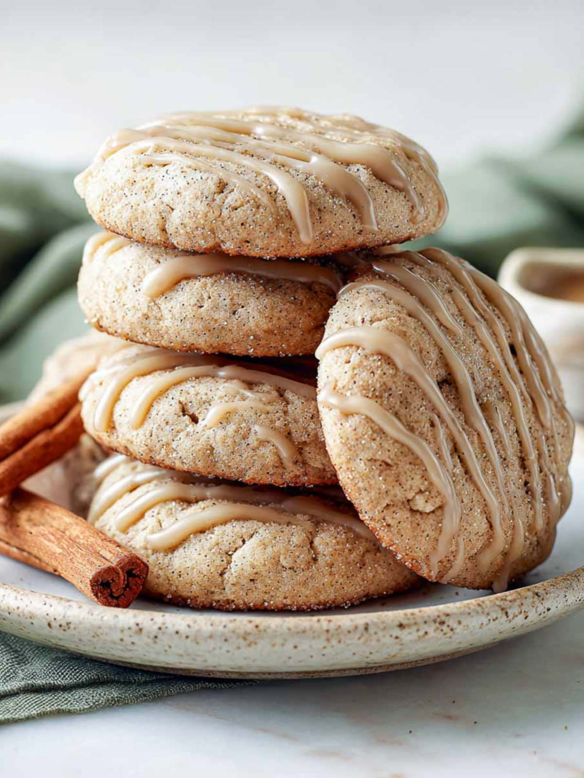 Side view of stacked apple cider cookies with brown sugar glaze and cinnamon sticks.