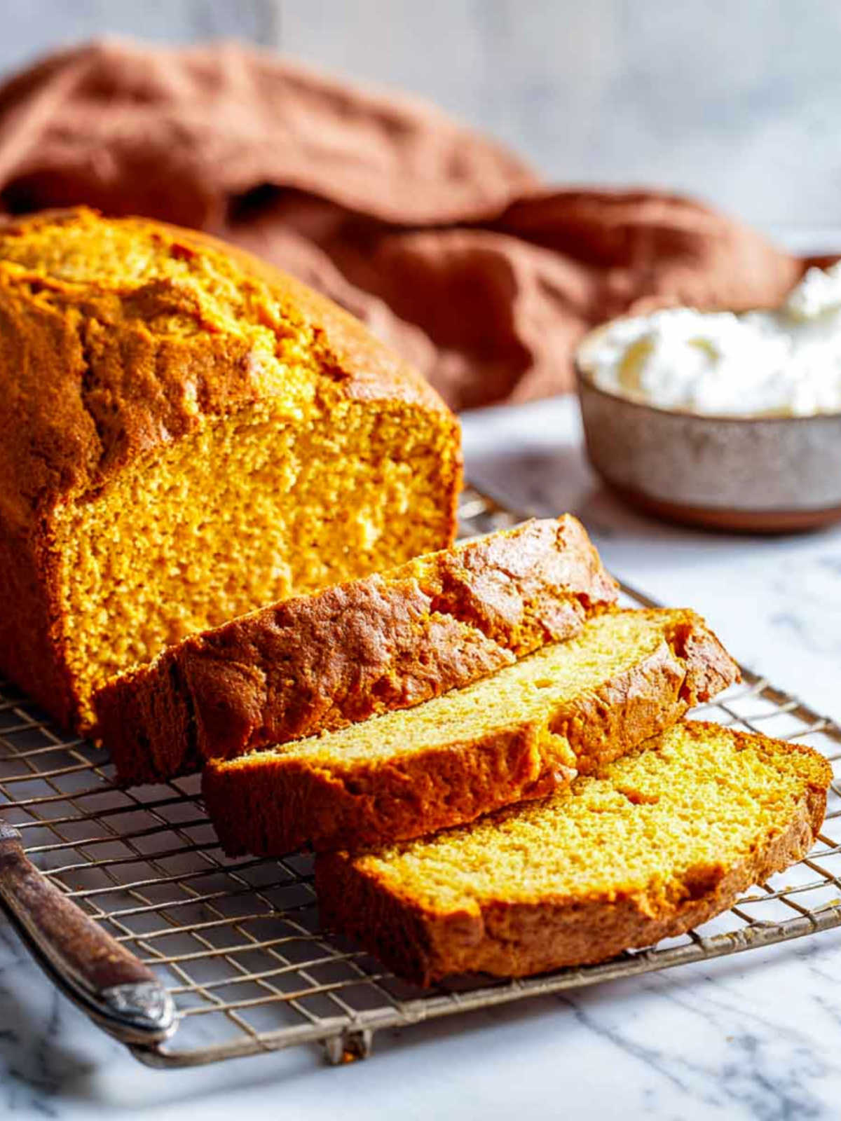 Close-up of moist pumpkin bread slices with golden crumb and rustic backdrop.