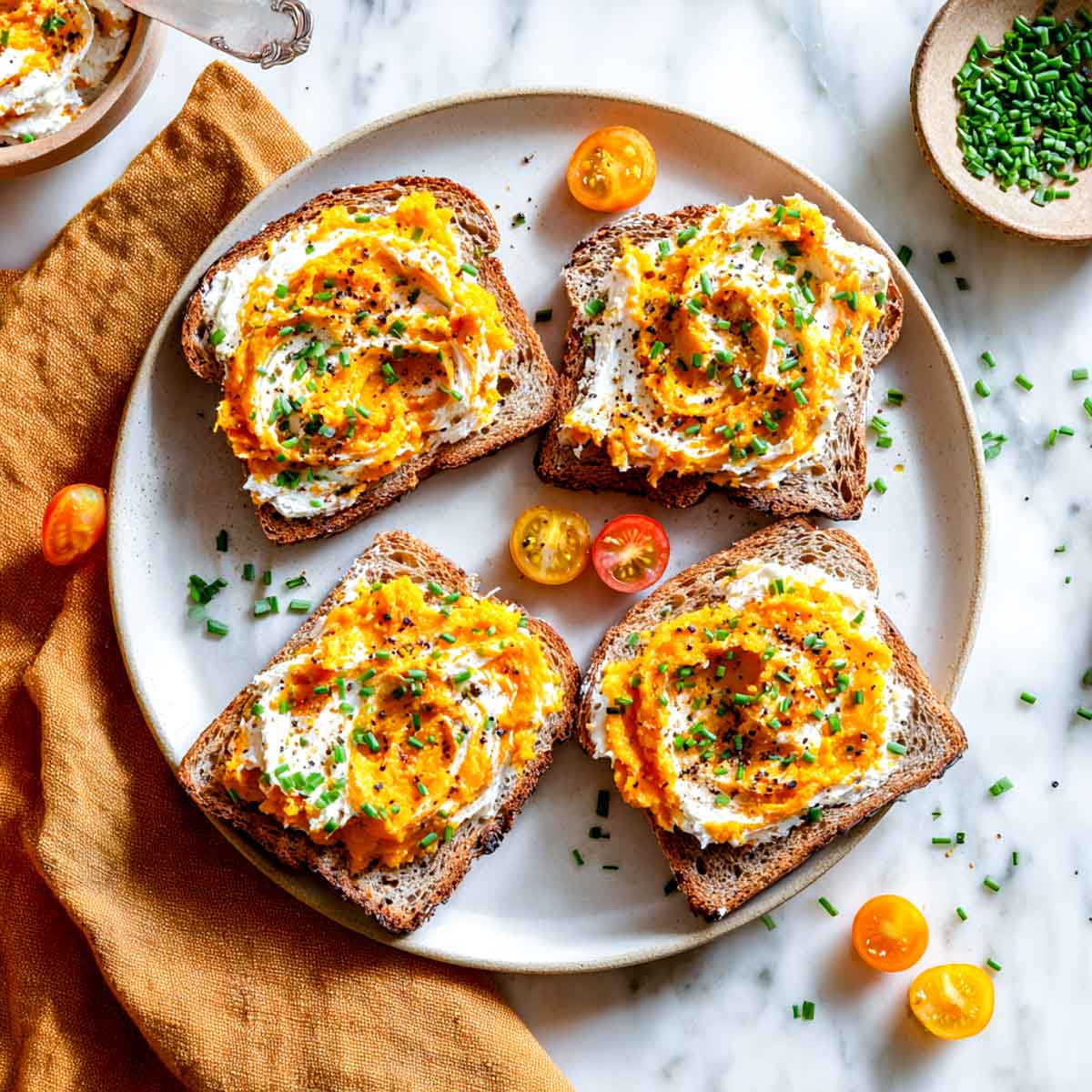 Four toast slices with cottage cheese and sweet potato swirl, topped with chives.