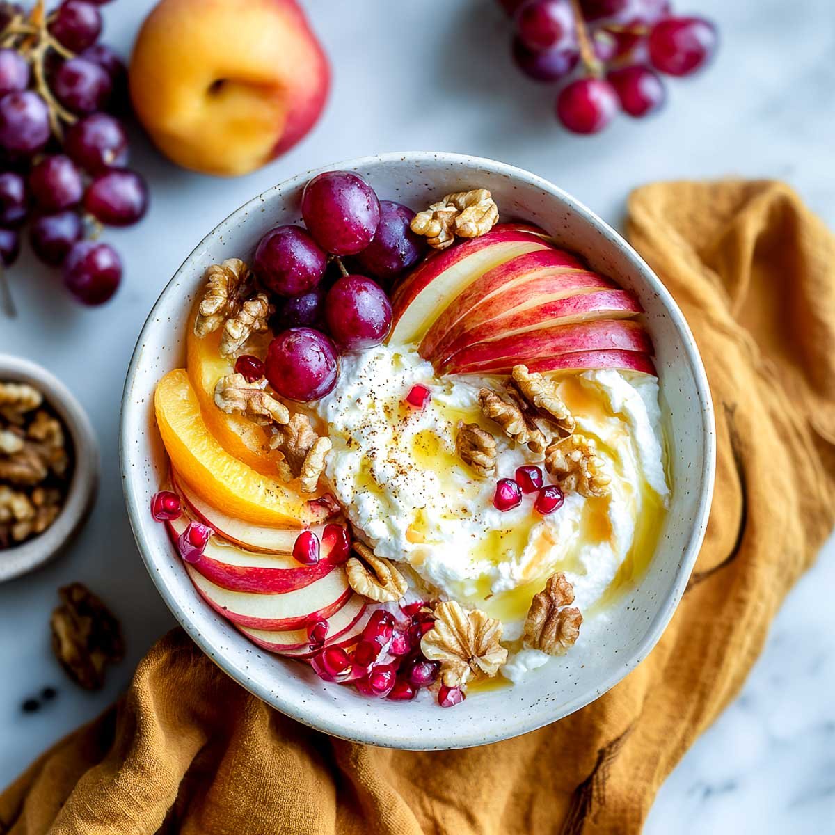 Cottage cheese bowl topped with fall fruits, walnuts, and maple syrup.