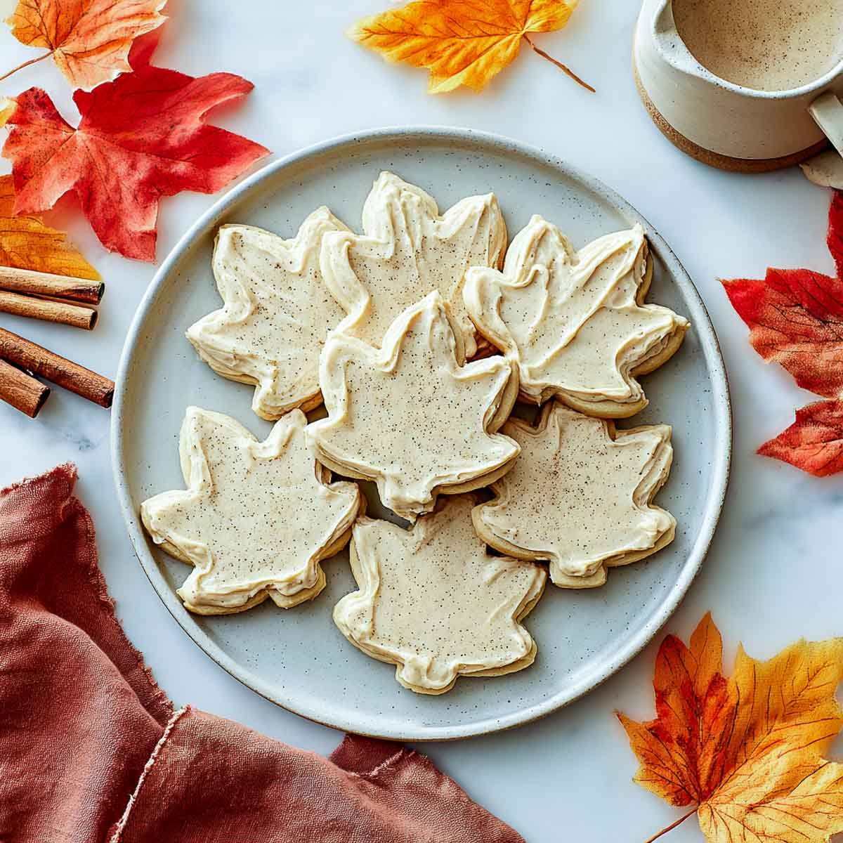 Fall leaf cookies with cinnamon buttercream frosting on a white plate