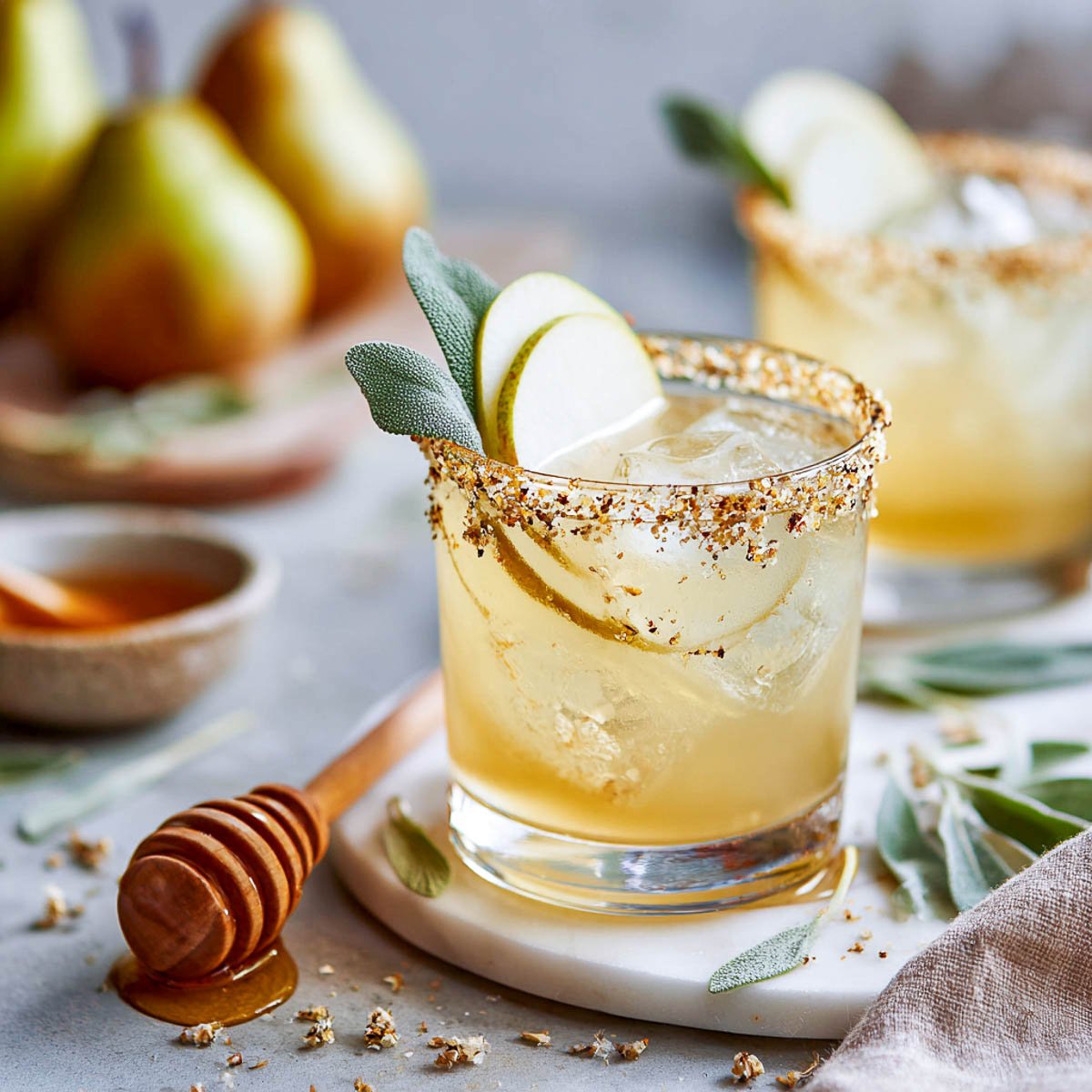 Honey pear margarita with sage leaves and pear slices on the rim.