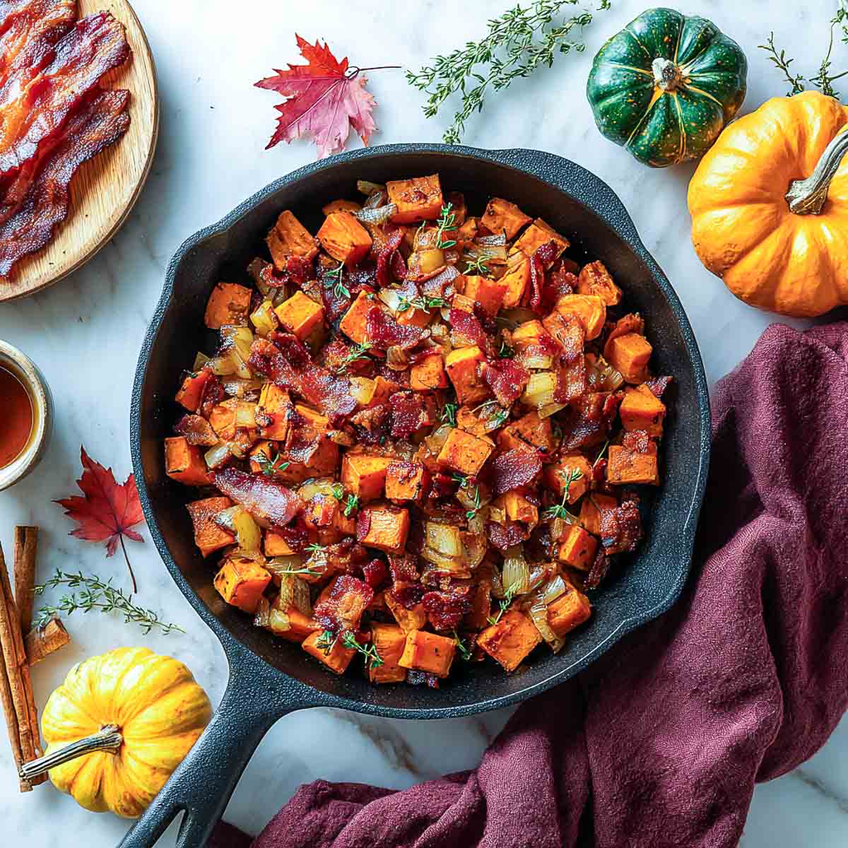 Cast iron skillet with maple bacon sweet potato hash on marble surface.
